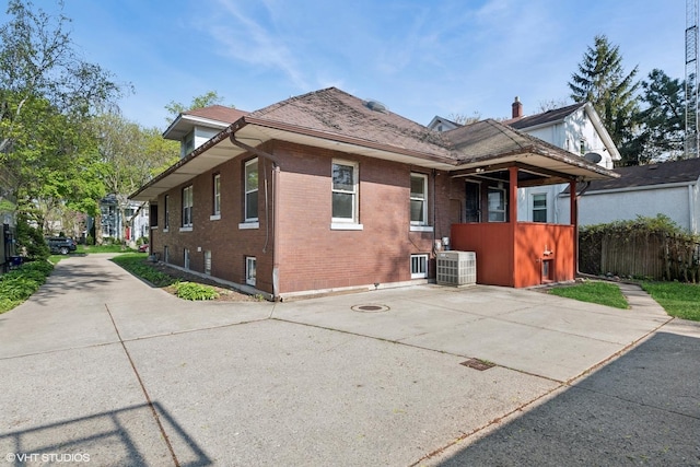 view of home's exterior featuring cooling unit, brick siding, and a shingled roof