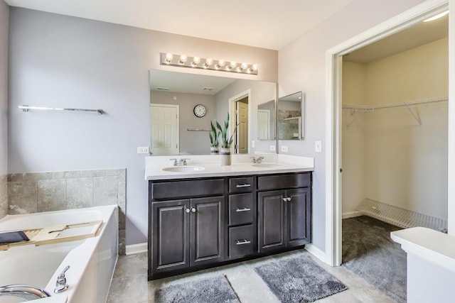 bathroom with a garden tub, double vanity, a spacious closet, and baseboards