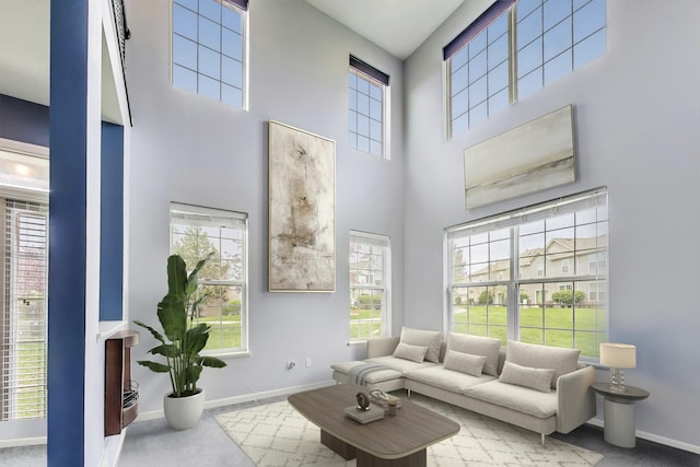 living area with a high ceiling, baseboards, and carpet floors