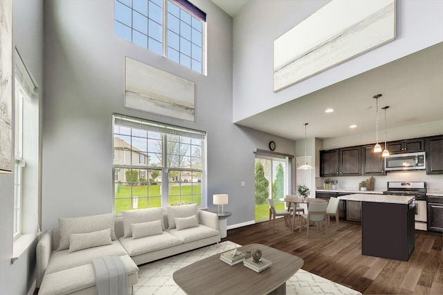 living area featuring a towering ceiling, dark wood-type flooring, recessed lighting, and baseboards