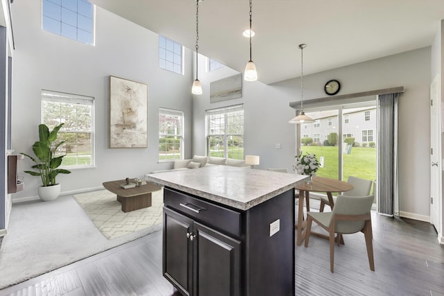kitchen featuring wood finished floors, light countertops, baseboards, open floor plan, and a high ceiling