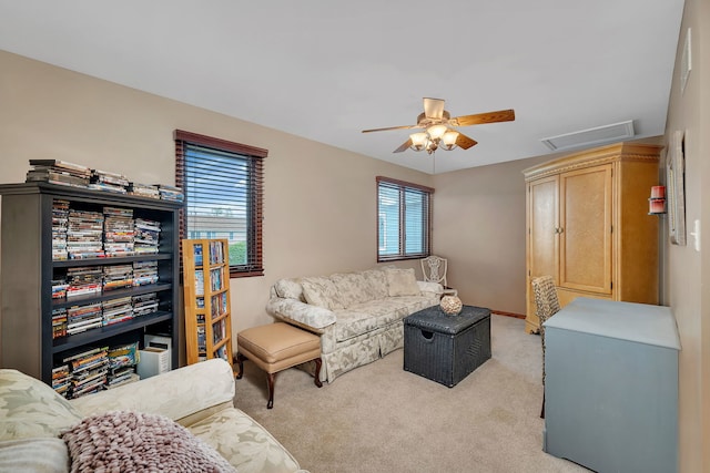 living area featuring a wealth of natural light, a ceiling fan, light colored carpet, and visible vents