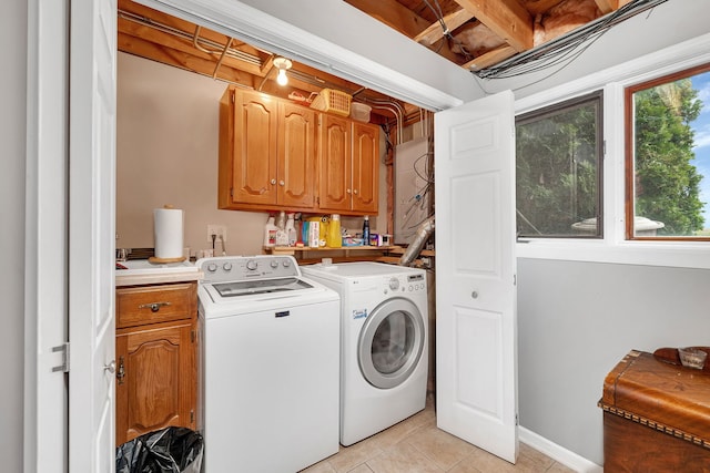 laundry room featuring cabinet space, light tile patterned flooring, and washing machine and clothes dryer