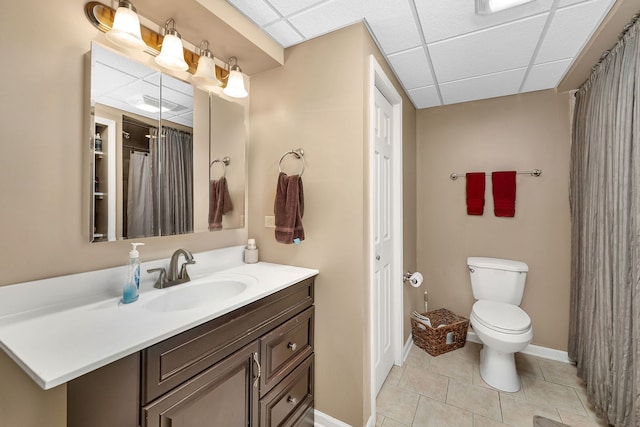 bathroom featuring toilet, baseboards, a paneled ceiling, and tile patterned flooring