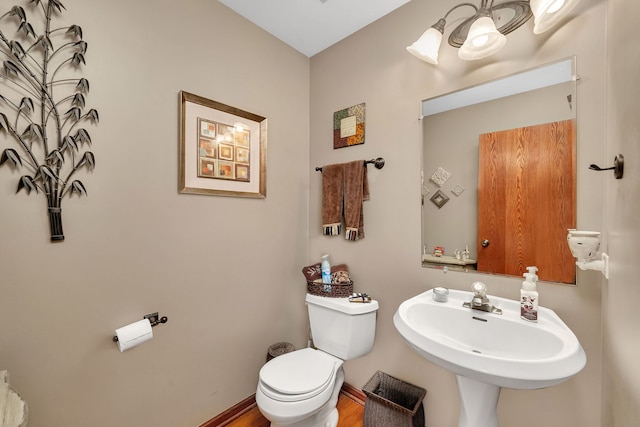bathroom with a sink, baseboards, toilet, and wood finished floors