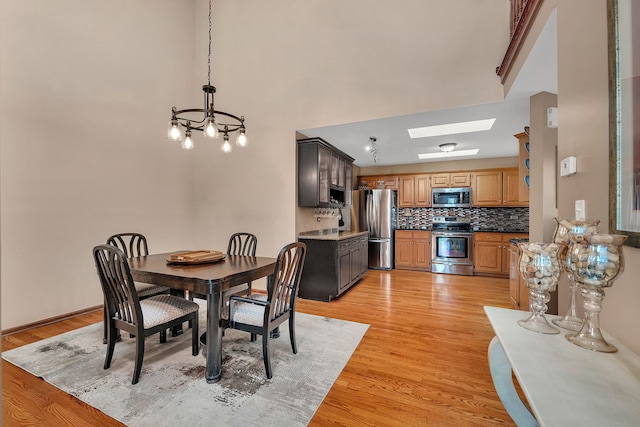 dining space featuring an inviting chandelier, a skylight, and light wood-style flooring