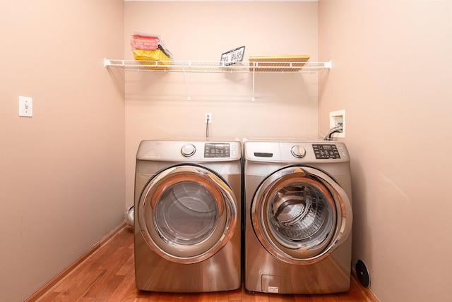 washroom with washer and dryer, laundry area, baseboards, and wood finished floors
