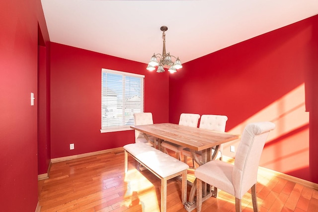 dining space with baseboards, light wood-type flooring, and a chandelier