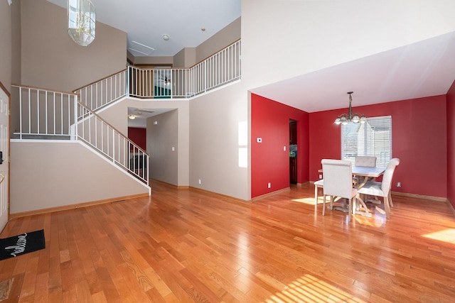 unfurnished living room featuring light wood-style floors, stairs, and a chandelier