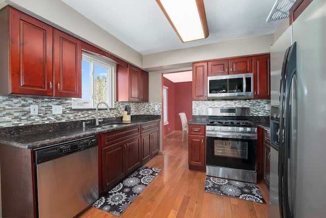 kitchen with a sink, stainless steel appliances, light wood-type flooring, and dark brown cabinets