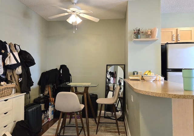 dining space with a textured ceiling, ceiling fan, and wood finished floors