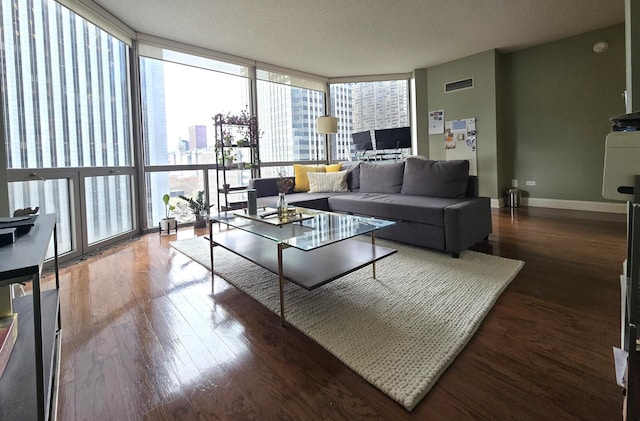living area with a textured ceiling, dark wood finished floors, baseboards, visible vents, and expansive windows