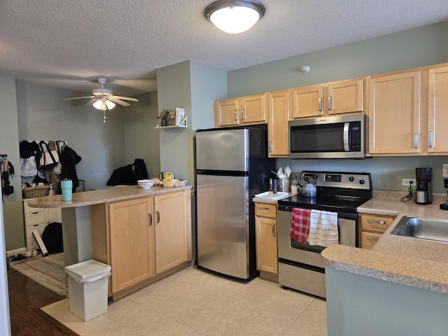 kitchen with ceiling fan, light countertops, a peninsula, light brown cabinets, and stainless steel appliances