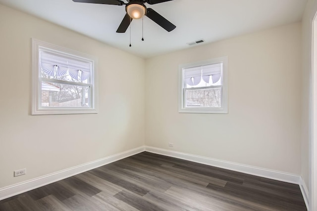 spare room featuring baseboards, visible vents, dark wood-style floors, and ceiling fan