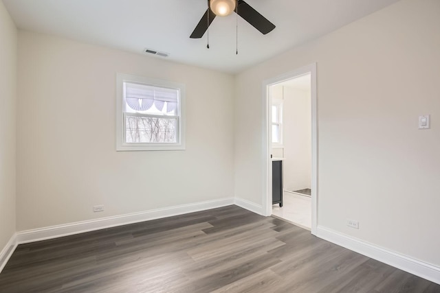 unfurnished bedroom featuring ceiling fan, visible vents, baseboards, dark wood-style floors, and ensuite bath
