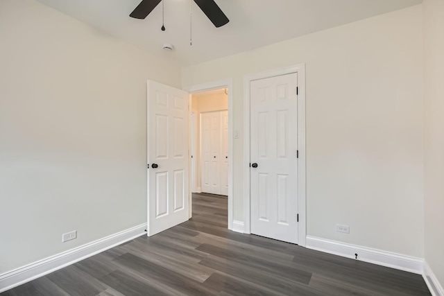 unfurnished bedroom with dark wood-style flooring, baseboards, ceiling fan, and a closet
