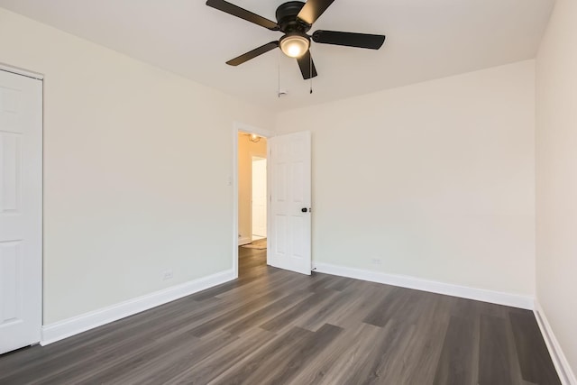 empty room featuring dark wood-type flooring, baseboards, and ceiling fan