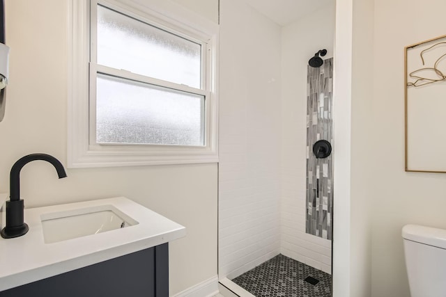 full bath featuring toilet, a tile shower, and a sink