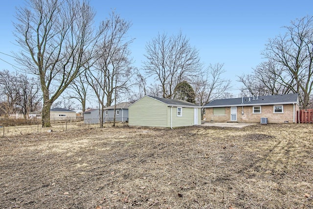 rear view of house with an outdoor structure, brick siding, fence, and a patio