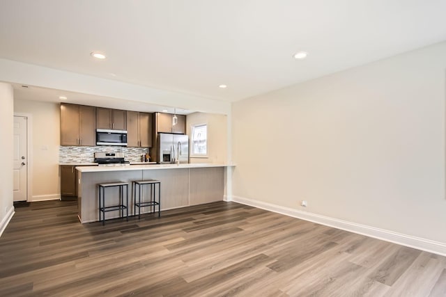 kitchen featuring baseboards, dark wood finished floors, backsplash, and stainless steel appliances