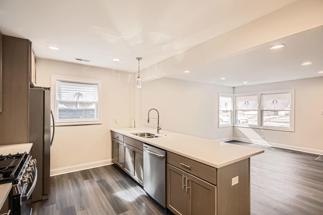 kitchen featuring visible vents, dark wood-style flooring, a peninsula, a sink, and appliances with stainless steel finishes