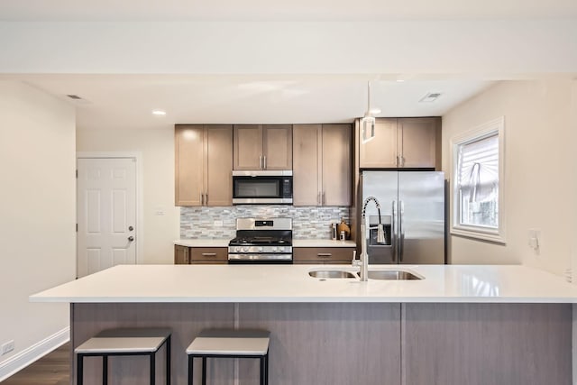 kitchen with light countertops, appliances with stainless steel finishes, backsplash, and a breakfast bar