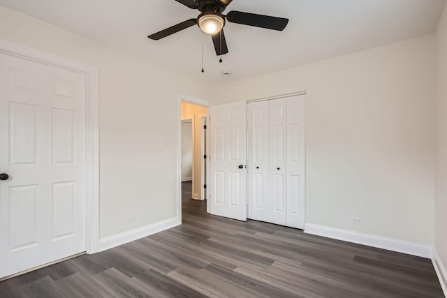 unfurnished bedroom with baseboards, dark wood-style floors, ceiling fan, and a closet