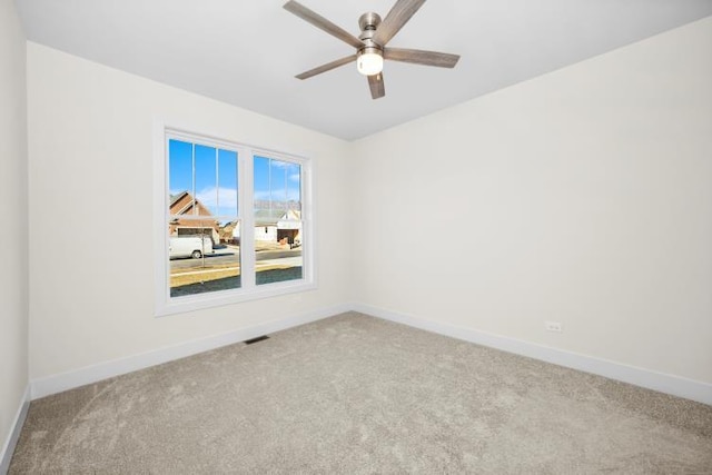 spare room with a ceiling fan, baseboards, visible vents, and carpet