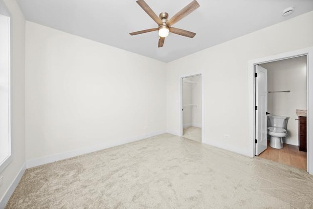 unfurnished bedroom with baseboards, carpet flooring, ensuite bath, and a spacious closet