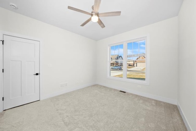 empty room with carpet flooring, baseboards, visible vents, and ceiling fan