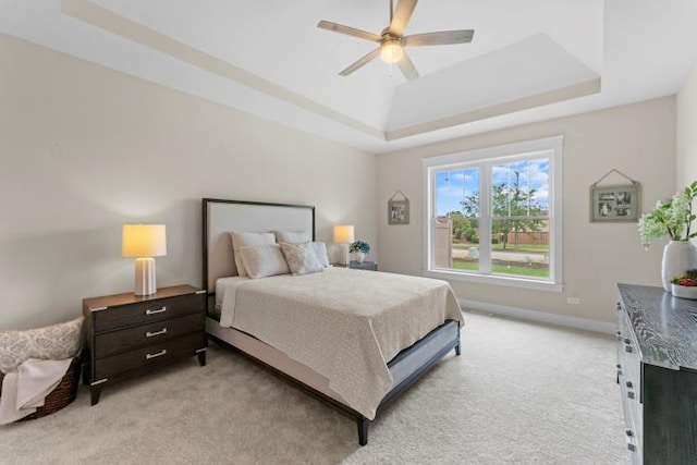 bedroom with baseboards, a ceiling fan, a raised ceiling, and light carpet