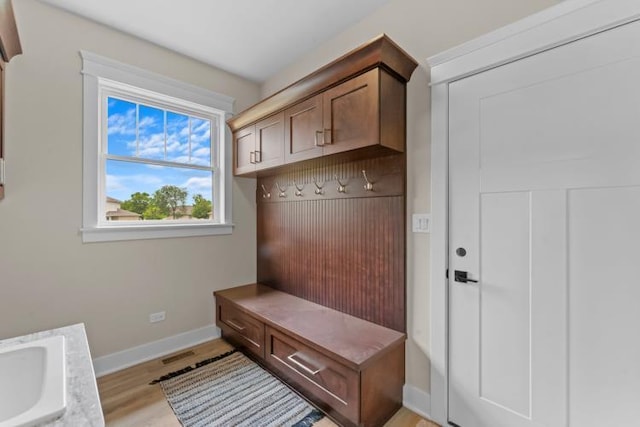 mudroom with baseboards, a sink, light wood-style flooring, and visible vents