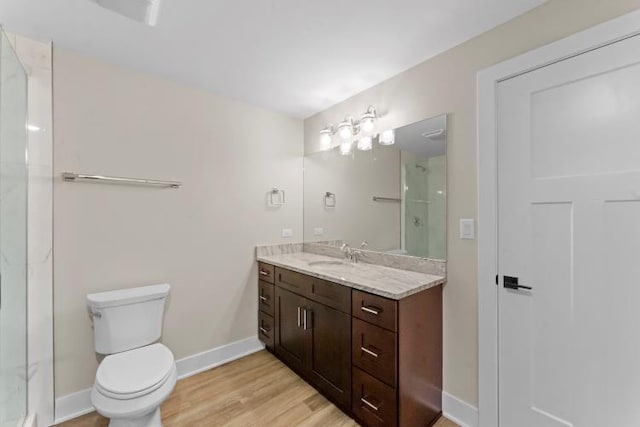 bathroom with a shower, wood finished floors, baseboards, vanity, and toilet