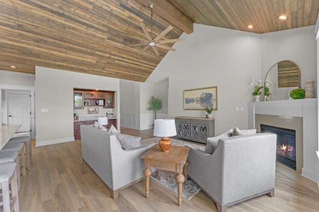 living room featuring wood ceiling, ceiling fan, high vaulted ceiling, a glass covered fireplace, and light wood-style flooring