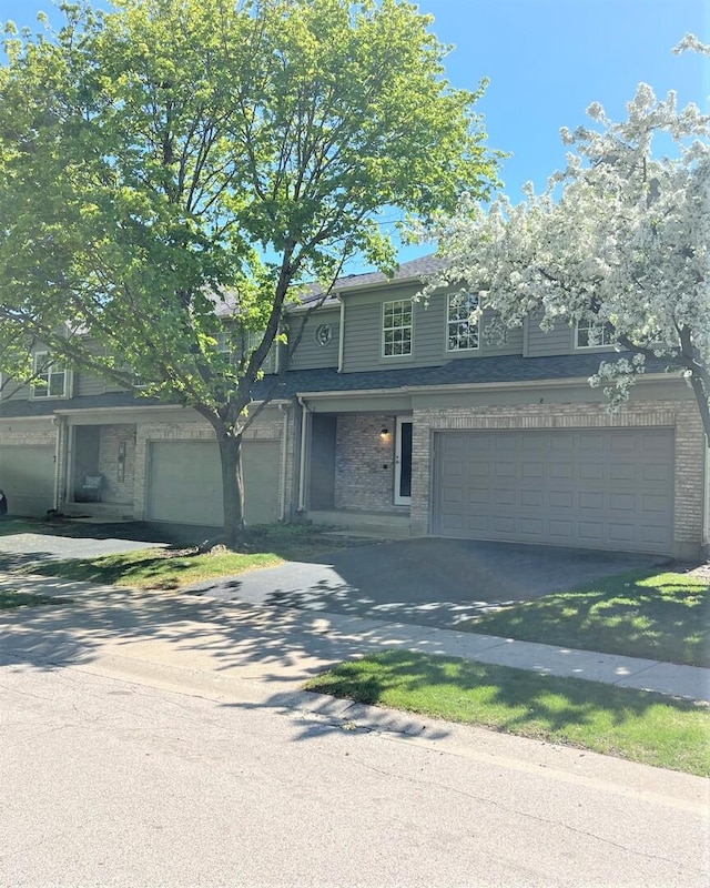 traditional home featuring an attached garage, concrete driveway, and brick siding