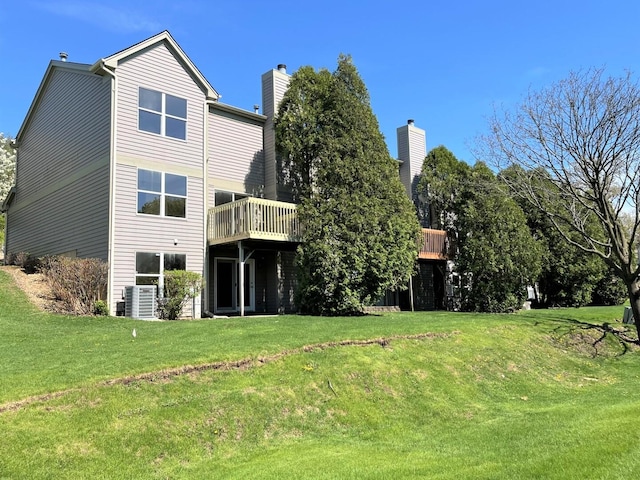 back of property featuring a wooden deck, a chimney, a yard, and central AC unit