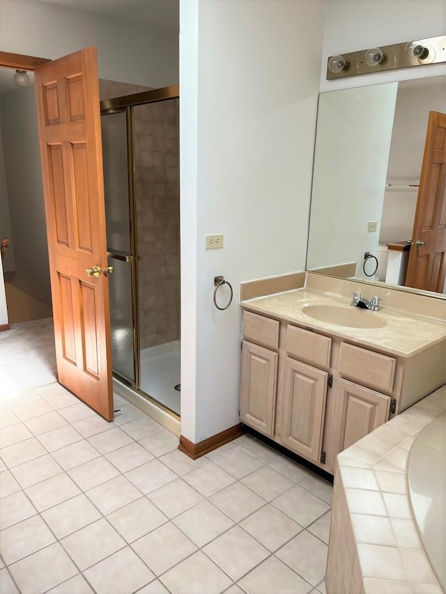 bathroom featuring vanity, tile patterned flooring, baseboards, and a stall shower