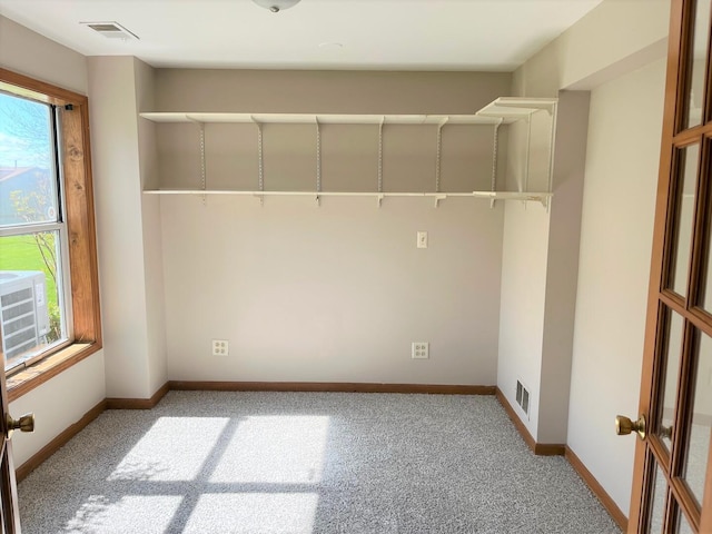 carpeted empty room featuring baseboards and visible vents