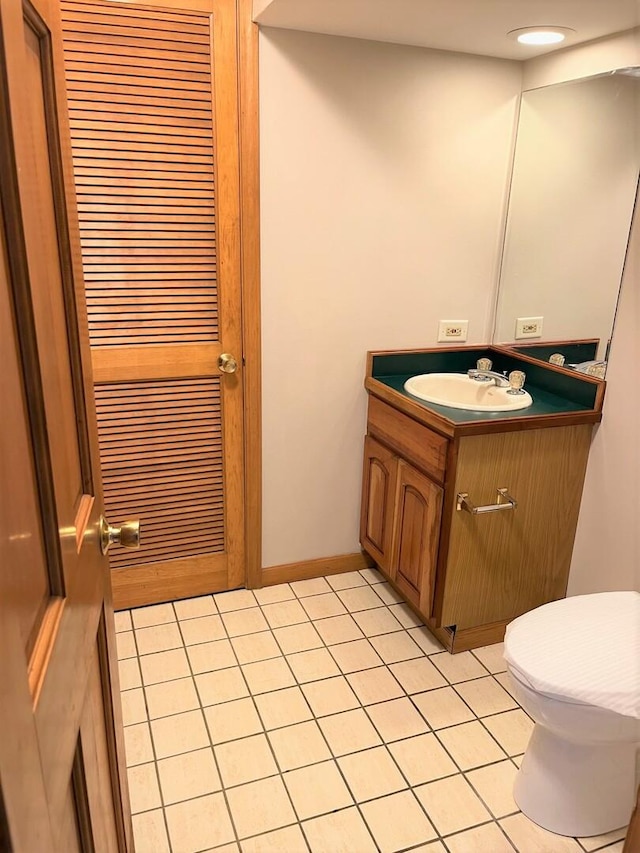 half bath featuring vanity, tile patterned flooring, and toilet