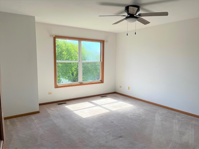 carpeted empty room featuring baseboards, visible vents, and ceiling fan
