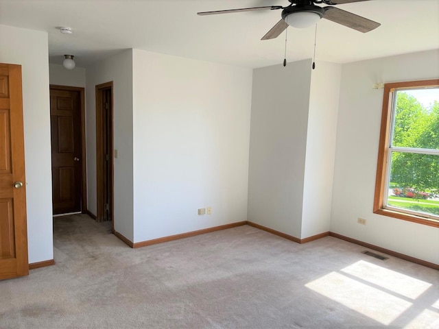spare room with baseboards, ceiling fan, light carpet, and visible vents
