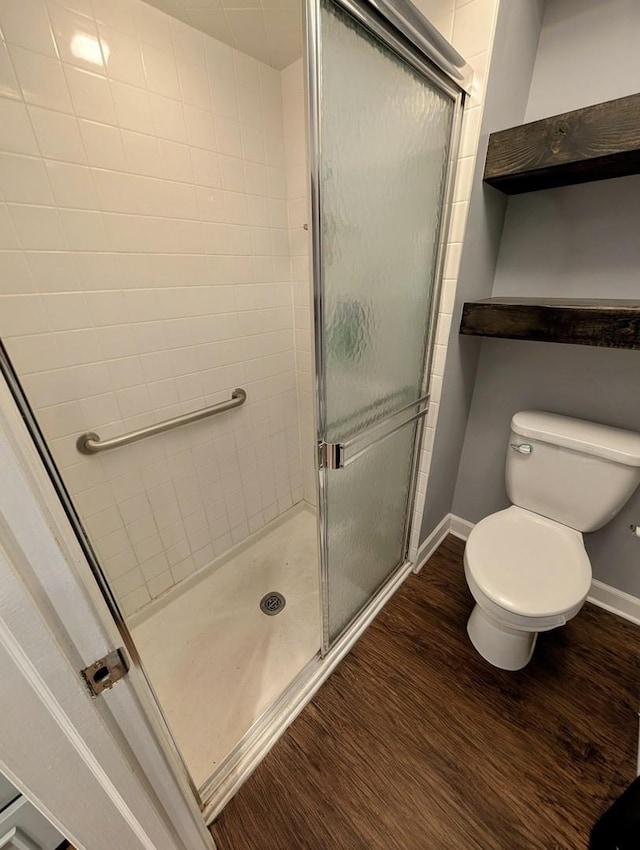 bathroom with baseboards, wood finished floors, and a shower stall