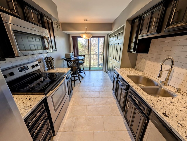 kitchen with a sink, appliances with stainless steel finishes, tasteful backsplash, and light stone countertops