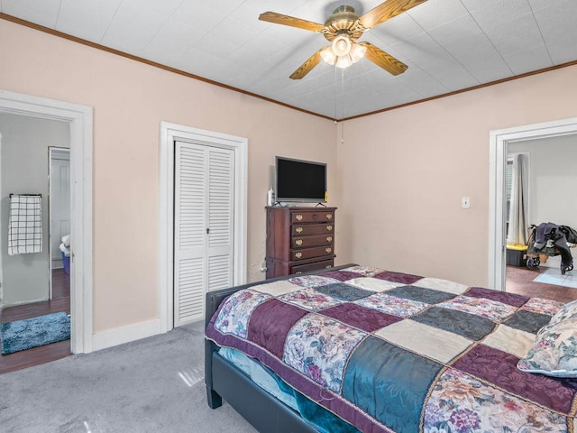 bedroom featuring ornamental molding, carpet floors, a closet, a ceiling fan, and baseboards