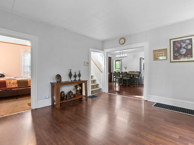 entrance foyer with stairs, a chandelier, wood finished floors, and baseboards
