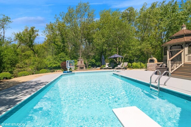 5632 Oakwood Cir, Long Grove, IL 60047 - outdoor pool with a patio, a gazebo, a diving board, fence, and view of wooded area