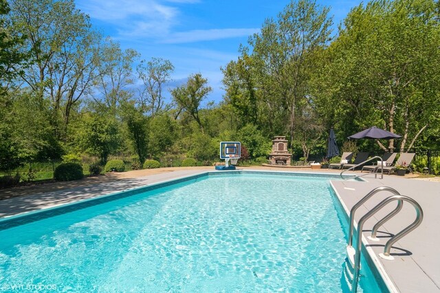 5632 Oakwood Cir, Long Grove, IL 60047 - swimming pool featuring a patio area, exterior fireplace, and view of scattered trees