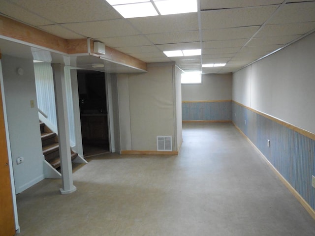 basement with stairway, a wainscoted wall, a paneled ceiling, and visible vents