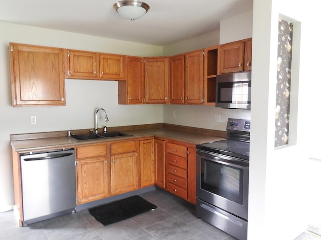 kitchen with a sink, appliances with stainless steel finishes, tile patterned flooring, and brown cabinetry