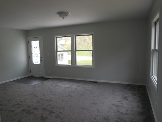 entrance foyer with baseboards, visible vents, and dark carpet